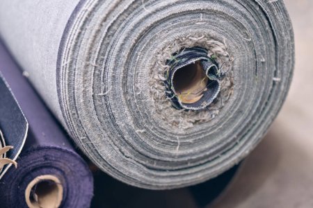Eine Rolle rohe Denim-Platten frisch vom Band in einer Denimfabrik. Industrielle Textil- und Modeherstellung. Stilvolles blaues Denim-Gewebe für Großhandel und Jeans. Symbolhafte blaue Hose.