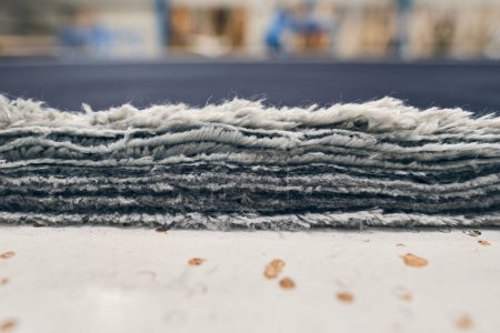 Ein Stapel rohe Jeansbezüge frisch vom Band in einer Denim-Fabrik. Industrielle Textil- und Modeherstellung. Stilvoller blauer Denim-Stoff für Großhandel und Jeans.