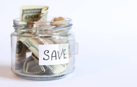 Photo for Glass jar with dollars on a white background. Piggy bank with banknotes, copy space. The concept of financial savings. Save money for the future - Royalty Free Image
