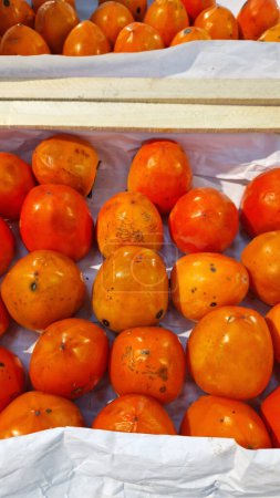 Selling persimmons in a store, close-up. Ripe persimmons are on sale in a supermarket. Food background. Berry. Healthy eating. Agricultural harvest concept