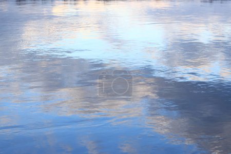 Reflet des nuages dans l'eau. La surface de l'eau dans un lac, une rivière ou une carrière inondée. Ondulations sur l'eau. Belle couleur d'eau. Contexte naturel