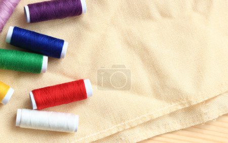 Photo for Spools of thread of different colors, top view. Set of various colorful sewing threads on fabric, close-up. Sewing - Royalty Free Image