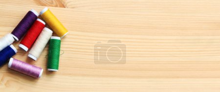 Photo for Spools of thread of different colors, top view. Set of various colorful sewing threads on a wooden table, close-up. Sewing - Royalty Free Image