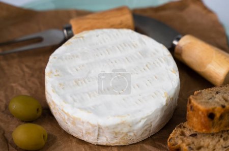 Photo for Camembert cheese, olives and sliced fresh baguette on the table. Close-up. Selective focus. - Royalty Free Image