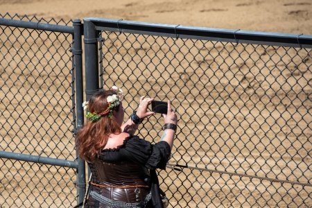 Photo for Folsom, CA, September 24, 2022. Lady in costume at the Folsom Renaissance Faire taking a picture with a cell phone - Royalty Free Image