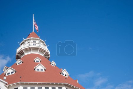 San Diego, CA. April 5, 2024. Hotel del Coronado roof and American flag, with plenty of blue sky copy space. Built in 1888, this hotel is a historical tourist attraction in the island of Coronado. 