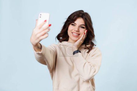 Téléchargez les photos : Adolescent fille blogger hes avoir du plaisir, prendre un selfie enregistrement vidéo à l'extérieur, regarder dans smartphone, avoir du plaisir à montrer des gestes se sent heureux, profiter de vidéocall. Vlogging, mode de vie - en image libre de droit