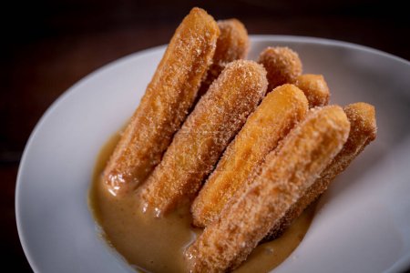 Churros sticks with caramel in a wooden background