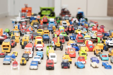 Photo for Toy cars, motorcycles, tractors, buses, pickups, many colorful small and large cars are arranged for play on the floor in the childrens room. Childhood concept. soft focus. - Royalty Free Image
