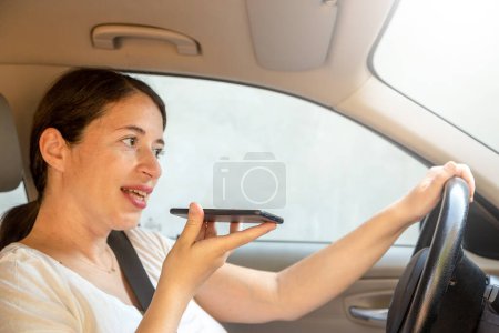 Téléchargez les photos : Femme enceinte insouciante conduisant sa voiture et parlant avec son téléphone portable - en image libre de droit