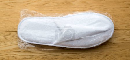Photo for Hotel bedroom slippers isolated on a wooden surface - Royalty Free Image