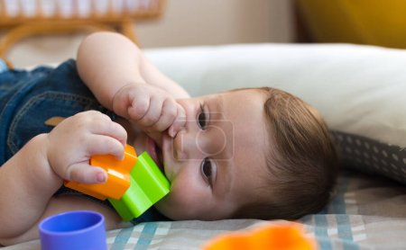 Photo for Happy and cheerful 8 months baby playing at home with colored bricks - Royalty Free Image