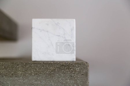 Téléchargez les photos : Cube en marbre de Carrare sur un bloc en béton ; composition de l'espace de copie - en image libre de droit