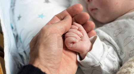 Foto de Cute newborn baby hand touching father's one; childhood and happiness theme - Imagen libre de derechos