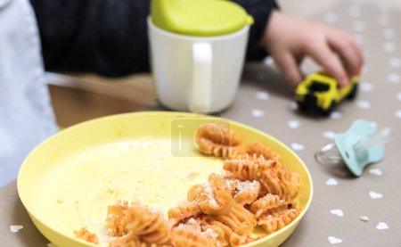 Photo for Two years old baby eating pasta with tomato sauce - Royalty Free Image