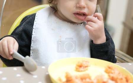 Foto de Bebé de dos años comiendo pasta con salsa de tomate - Imagen libre de derechos