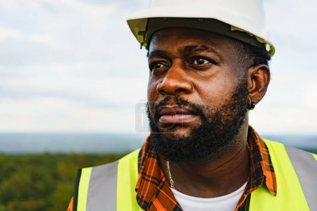 Photo for Close up portrait of black optimistic engineer man smiling and looking to the field while working outdoor. - Royalty Free Image