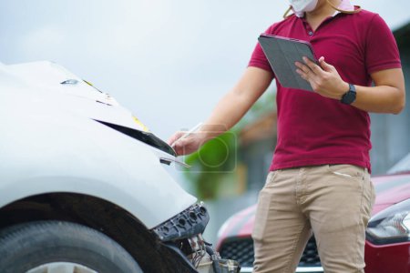Photo for Side view of writing on tablet while insurance agent examining car after accident - Royalty Free Image