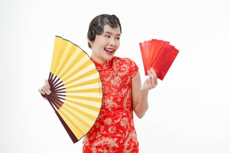 Photo for Portrait of young attractive Chinese woman smiling happily holding big yellow fan, ang pao, red envelopes wearing cheongsam looking happy, celebrate Chinese lunar new year, festive season holiday. - Royalty Free Image