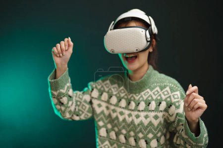 Foto de Mujer asiática que usa auriculares VR con fondo de luz de neón para obtener una experiencia emocionante de la tecnología de realidad virtual, entretenimiento de simulación 3D digital en el hogar, VR Simulator for Exercise concept. - Imagen libre de derechos