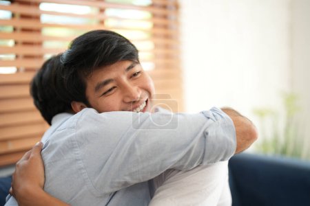 Téléchargez les photos : Couple jeune homme assis dans le salon pendant qu'ils embrassent câlin après avoir eu la demande en mariage. - en image libre de droit