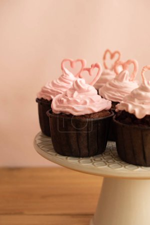 Photo for Many chocolate cupcakes topped with pink cream frosting and a heart-shaped chocolate on top of each of them. - Royalty Free Image