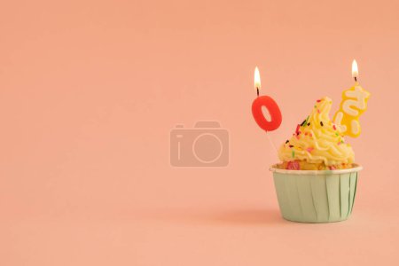 Photo for A birthday cupcake with zero-year candles on colral poink background - Royalty Free Image