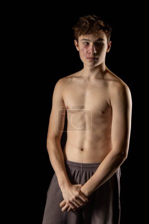 Photo for A portrait of a 17 year old shirtless muscular teenage boy against  a black background - Royalty Free Image