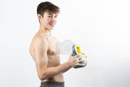 Photo for A 17 year old shirtless muscular teenage boy holding a kettlebell - Royalty Free Image
