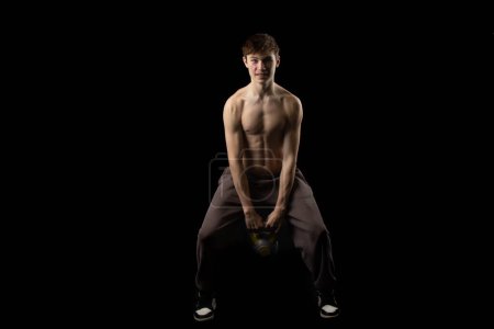 Photo for A 17 year old shirtless muscular teenage boy doing kettlebell swings - Royalty Free Image