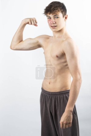 Photo for A 17 year old shirtless muscular teenage boy flexing his arm muscles - Royalty Free Image