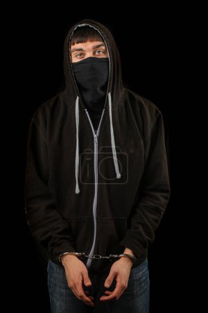 Foto de Arrestado adolescente esposado con una máscara y una sudadera con capucha - Imagen libre de derechos