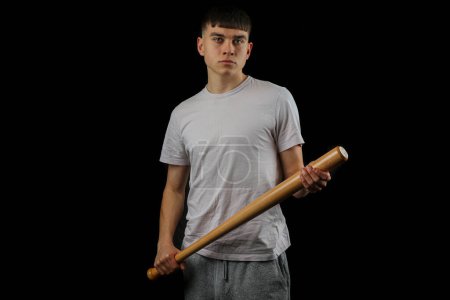 Foto de Un adolescente con un bate de béisbol mirando amenazante contra un fondo negro - Imagen libre de derechos