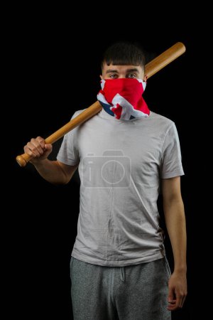 Foto de Adolescente con una máscara de bandera británica sosteniendo un bate de béisbol sobre un fondo negro - Imagen libre de derechos