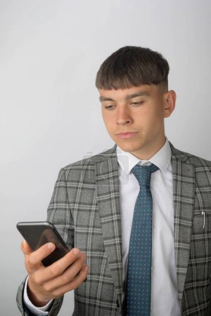Foto de Joven empresario con traje y corbata leyendo un mensaje en su teléfono - Imagen libre de derechos