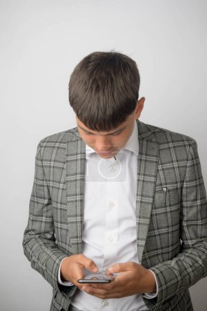 Foto de Joven empresario con chaqueta de traje y camisa de cuello abierto sin corbata escribiendo en su teléfono - Imagen libre de derechos