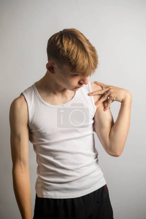Portrait d'un adolescent caucasien de 14 ans portant un gilet sans manches fléchissant son biceps