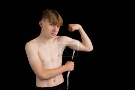 Photo for Portrait of a sporty shirtless teenage boy measuring his bicep - Royalty Free Image