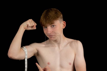 Photo for Portrait of a sporty shirtless teenage boy measuring his bicep - Royalty Free Image