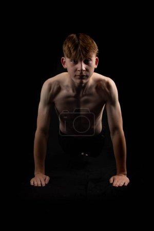 Porträt eines sportlichen Jungen ohne Hemd, der von vorne Liegestütze macht