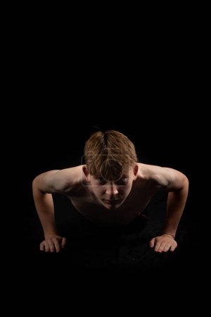 Photo for Portrait of a sporty shirtless teenage boy doing press ups from the front - Royalty Free Image