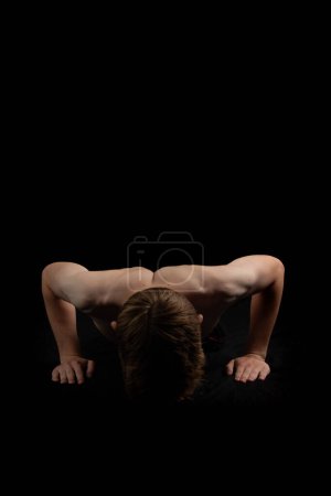 Portrait of a sporty shirtless teenage boy doing press ups from the front