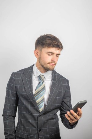 Foto de Retrato de un joven empresario en traje y corbata leyendo un mensaje en su teléfono - Imagen libre de derechos