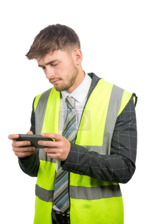 Foto de Retrato de un hombre de negocios con traje, con un chaleco de alta visibilidad leyendo mensajes en un teléfono móvil - Imagen libre de derechos