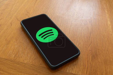 Foto de Londres, Reino Unido, 5 de septiembre de 2023 Un teléfono móvil en una mesa de madera que muestra el logotipo de Spotify streaming services - Imagen libre de derechos