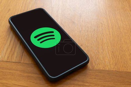 Foto de Londres, Reino Unido, 5 de septiembre de 2023 Un teléfono móvil en una mesa de madera que muestra el logotipo de Spotify streaming services - Imagen libre de derechos