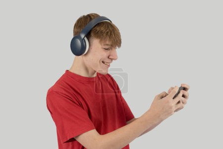 Foto de Adolescente con auriculares jugando un juego en su teléfono móvil - Imagen libre de derechos