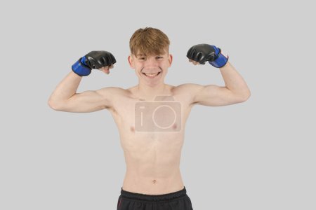 Photo for Shirtless male teenage MMA fighter flexing his arm mucles - Royalty Free Image