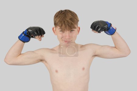 Photo for Shirtless male teenage MMA fighter flexing his arm mucles - Royalty Free Image