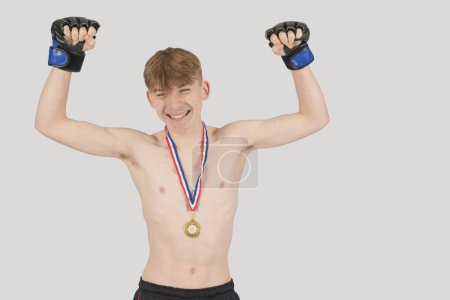 Photo for Shirtless male teenage MMA fighter celebrating with a medal - Royalty Free Image